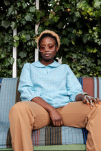 Load image into Gallery viewer, Lady sits wearing a checked peter-pan collar shirt with 3/4 lengths sleeves gathered at the cuffs