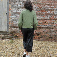 Load image into Gallery viewer, Back view of model wearing a collared blouse with long sleeves, gathered into a cuff