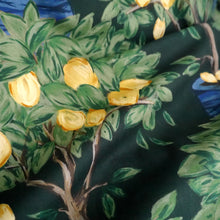 Load image into Gallery viewer, Close-up of cotton lawn fabric with a lemon tree pattern featuring green leaves and yellow lemons, in soft drape