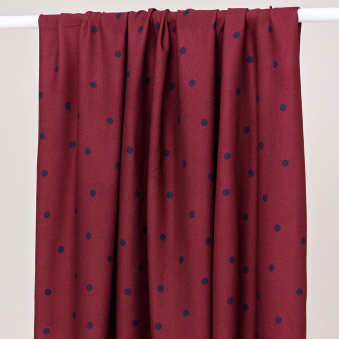 EcoVero Viscose Fabric with dots print hangs over a rail