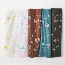 Load image into Gallery viewer, Five bolts stand against wall of Organic Cotton Double Gauze fabric in different colourways with floral pattern