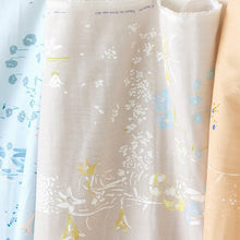 Load image into Gallery viewer, Fabric bolts slightly rolled out against the wall, shows Organic Cotton Double Gauze fabric with floral print