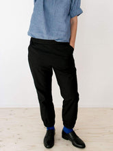 Load image into Gallery viewer, Lady stood up wearing black trousers, elasticated cuffs at ankles. Worn with a light blue puff top, elasticated cuffs on short sleeves.