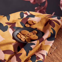 Load image into Gallery viewer, Folded Seraphine Ochre EvoVero Viscose fabric displayed with a bowl of matching colour buttons on top.