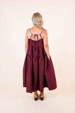 Load image into Gallery viewer, Back view of lady wearing Celestia tier dress with hands in pockets, and drawstring fastening at back neckline
