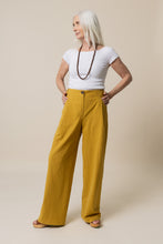 Load image into Gallery viewer, Lady stands wearing wide-legged Mitchell Trousers, with hands on hips