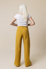 Load image into Gallery viewer, Back view of lady standing wearing wide-legged Mitchell Trousers, shows two welted pockets at hip level
