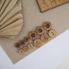 Load image into Gallery viewer, A group of 12mm coconut buttons sit next to a group of 20mm coconut buttons, showing both the fronts and the backs of the buttons