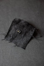 Load image into Gallery viewer, A single Scuttle Black Cotton Button sewn onto a square piece of linen.