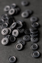 Load image into Gallery viewer, Collection of Scuttle Black Cotton buttons with four holes piled on surface.