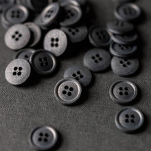 Load image into Gallery viewer, Collection of Scuttle Black Cotton buttons with four holes piled on surface.