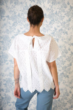 Load image into Gallery viewer, Back view of lady standing, wearing a top with a yoke which opens at the centre-back and is fastened with a bow and long ties hanging down her back