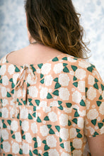 Load image into Gallery viewer, Back view of lady wearing a short sleeve top with inverted box pleat into a yoke, open at centre-back, fastened with knotted ties