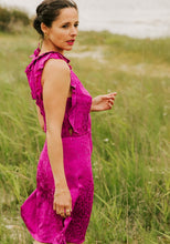 Load image into Gallery viewer, Lady wears a sleeveless Luz Dress with ruffles along the neckline, and around the V shaped armholes