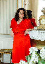 Load image into Gallery viewer, Lady leans on mantelpiece wearing a V-neck button front blouse and wrap skirt