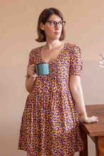 Load image into Gallery viewer, Lady stands holding cup, wears a wide V neck, short sleeve dress, made with Mandarine EcoVero fabric