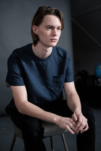 Load image into Gallery viewer, Male sits on chair wearing a single colour Tee Shirt