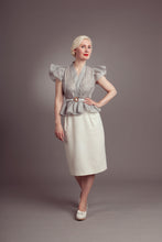 Load image into Gallery viewer, Full length view of lady wearing striped blouse with peplum at waist, and frilly puff shoulder sleeves. Worn with plain pencil skirt.