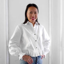 Load image into Gallery viewer, Lady wears a collared shirt with gathered frill edging at waist and at cuffs, made with Organic cotton poplin fabric