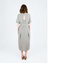 Load image into Gallery viewer, Back view of lady wearing Tide Dress showing two pleats overlapping a key-hole neckline, tie at waist