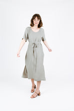 Load image into Gallery viewer, Front view of lady turning wearing Tide dress to show side splits at skirt, a round neckline and waist tie