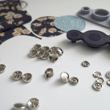 Load image into Gallery viewer, 11mm metal cover button blanks displayed next to cover tool and circular pieces of fabric