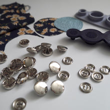 Load image into Gallery viewer, 13mm metal cover button blanks displayed next to cover tool and circular pieces of fabric
