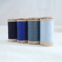 Load image into Gallery viewer, Four wooden reels of organic cotton sewing threads. Navy, Royal Blue, Stormy Blue, Ice.