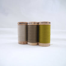 Load image into Gallery viewer, Three wooden reels of organic cotton sewing thread in Ecru, Khaki and Celery colours