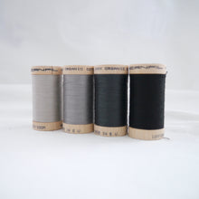 Load image into Gallery viewer, Four wooden reels of organic cotton sewing thread in Sand, Steel Grey, Charcoal and Black Onyx colours