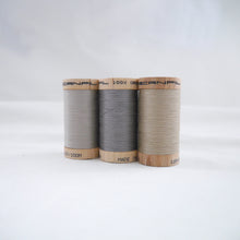 Load image into Gallery viewer, Three wooden reels of organic cotton sewing thread in Sand, Steel Grey and Ecru colours