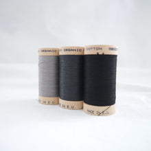 Load image into Gallery viewer, Three wooden reels of organic cotton sewing thread in Steel Grey, Charcoal and Black Onyx colours