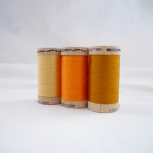 Load image into Gallery viewer, Wooden reels of organic cotton sewing thread in Straw, Tangerine and Gold Ochre colours