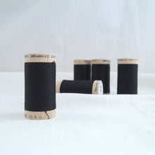Load image into Gallery viewer, Five wooden reels of organic cotton sewing thread in black.