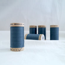 Load image into Gallery viewer, Five wooden reels of organic cotton sewing thread in a dusty Stormy blue colour.