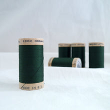 Load image into Gallery viewer, Five wooden reels of organic cotton sewing thread in a forest green colour.