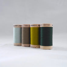 Load image into Gallery viewer, Line of four wooden reels of organic cotton sewing threads in mint, khaki, celery and forest green colours.