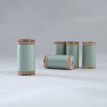 Load image into Gallery viewer, Four wooden reels of organic cotton sewing threads in a light mint green colour