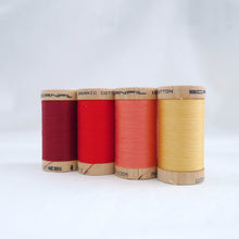Load image into Gallery viewer, Four wooden reels of Scanfil Organic Cotton Thread in Wine, Ruby, Salmon, Straw colours.