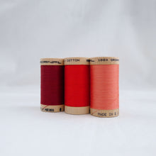 Load image into Gallery viewer, Three wooden reels of Scanfil Organic Cotton Thread in Wine, Ruby, Salmon colours.