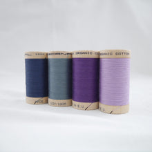 Load image into Gallery viewer, Four wooden reels of Scanfil Organic Cotton Thread in Sapphire, Dusk, Purple and Lavender colours.