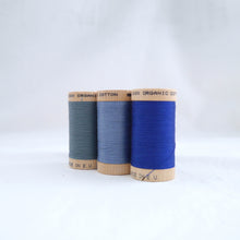 Load image into Gallery viewer, Three wooden reels of Scanfil Organic Cotton Thread in Stormy Blue, Dusk, Ocean colours.