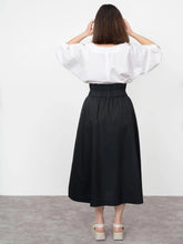 Load image into Gallery viewer, Back view of lady wearing the V-Neck Cuff Top tucked into a skirt, round neckline