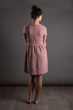 Load image into Gallery viewer, Back view of lady standing, wearing fitted short sleeve bodice, with gathered waistline skirt, knee length dress.