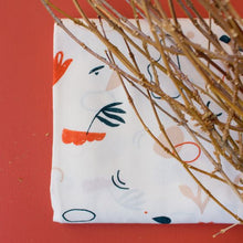 Load image into Gallery viewer, Folded fabric piece shows pattern of leafy shapes against a light contrasting colour background.