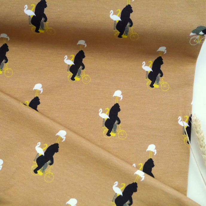 Fabric softly folded shows French Terry fabric with silhouettes of animals on bicycles