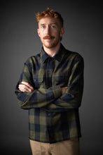 Load image into Gallery viewer, Male wears a checked long sleeved collared shirt, arms crossed across front
