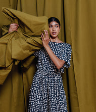 Load image into Gallery viewer, Model stands holding fabric, wearing a jumpsuit, made in Atelier Brunette&#39;s Ekko Viscose fabric.
