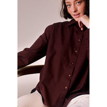 Load image into Gallery viewer, Model sits in chair, wearing button-up shirt, made with Oxford Cotton fabric
