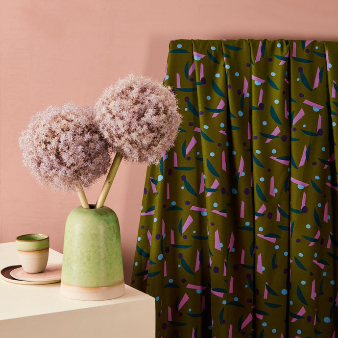 Viscose fabric with bold shapes pattern hangs by a table with a vase